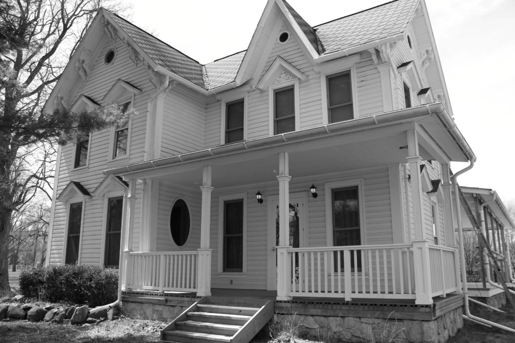 the author's dad's house, circa 2015. A seventeenth century farm house with a wrap around stone porch and hand-made wood detailing around the windows.